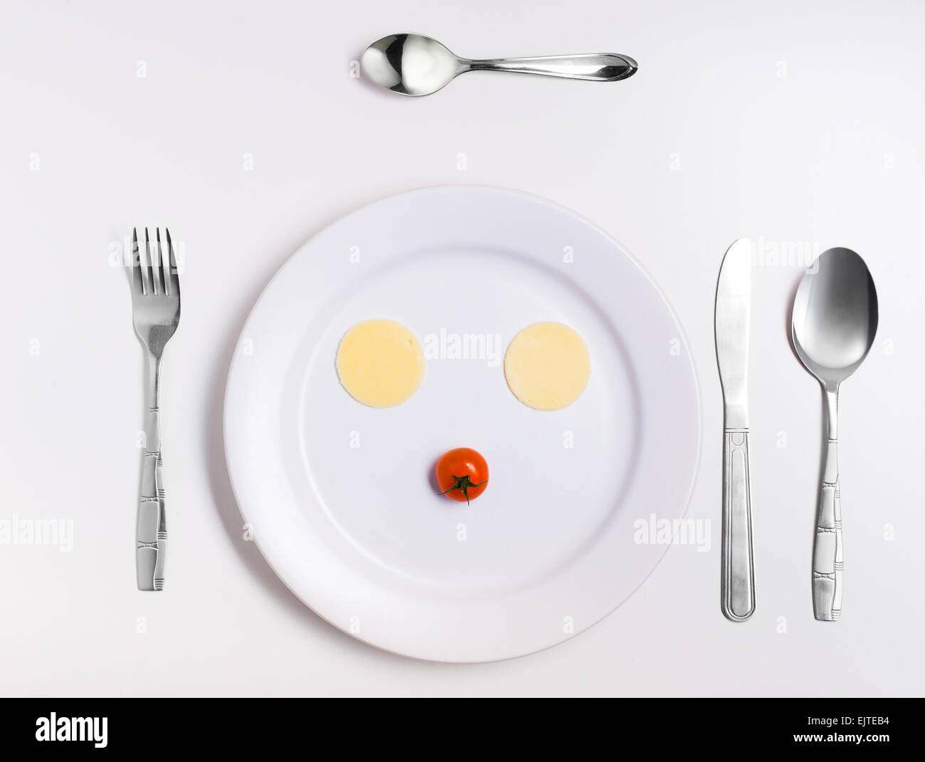 emoticon food, made from cheese, tomatoes, on a plate with cutlery Stock Photo