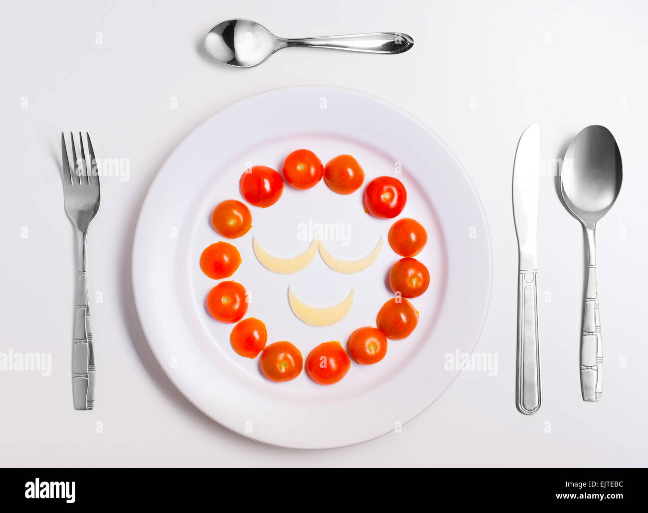 smiley face emoticon food, made from cheese and tomatoes, on a plate with cutlery, isolated Stock Photo