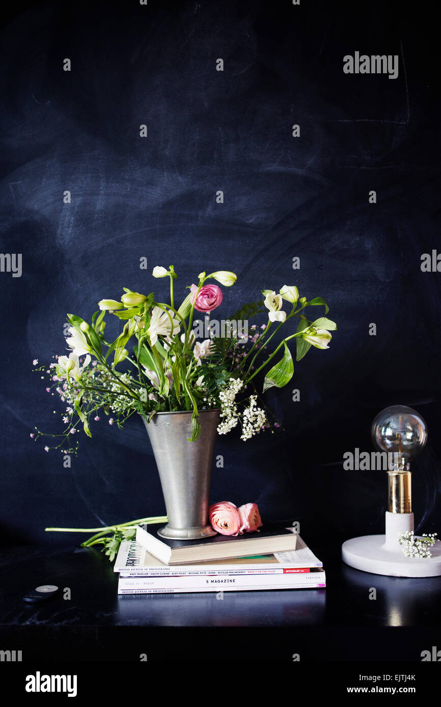 Electric lamp with books and flower vase on table in class Stock Photo