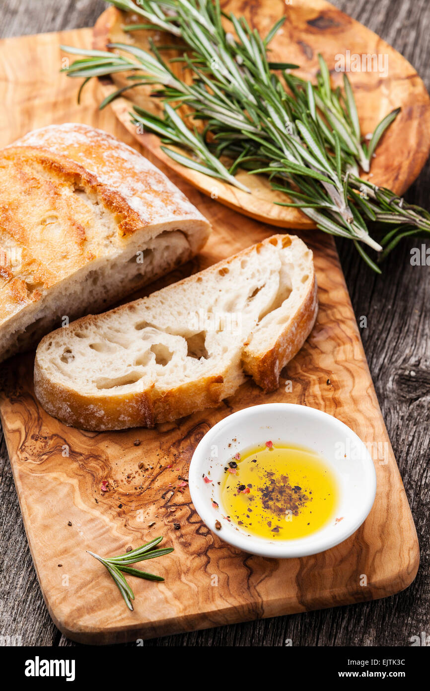 Sliced bread Ciabatta and extra virgin Olive oil on olive wood cookware background Stock Photo