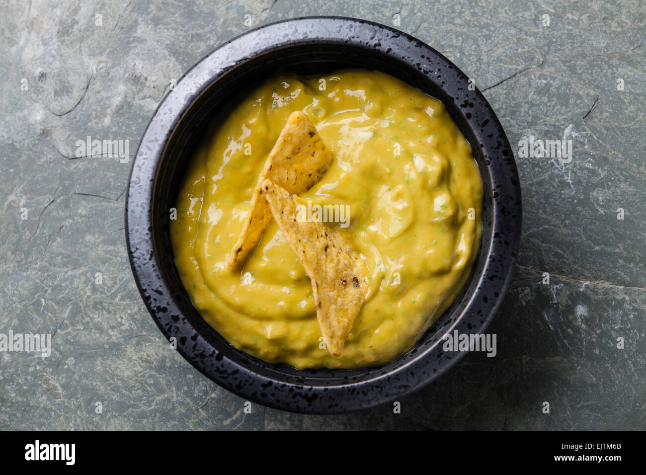 Fresh guacamole dip with nachos chips on stone slate background Stock Photo