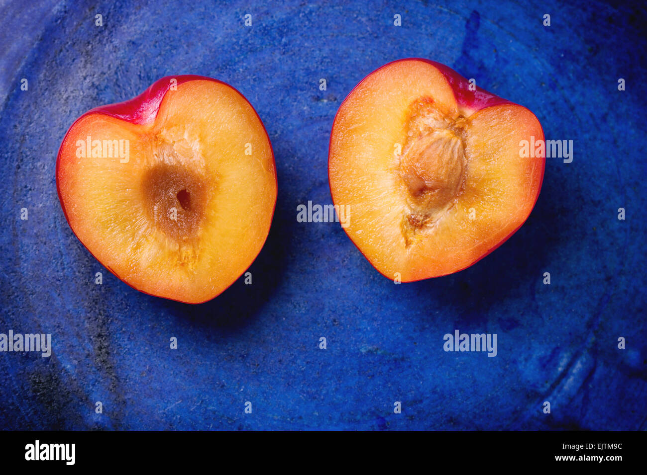 Nectarine halves in the shape of heart over blue ceramic background