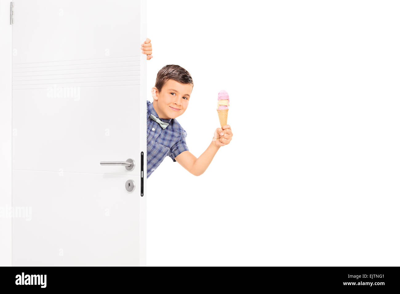 Little boy holding and ice cream behind a white door and looking at the camera isolated on white background Stock Photo