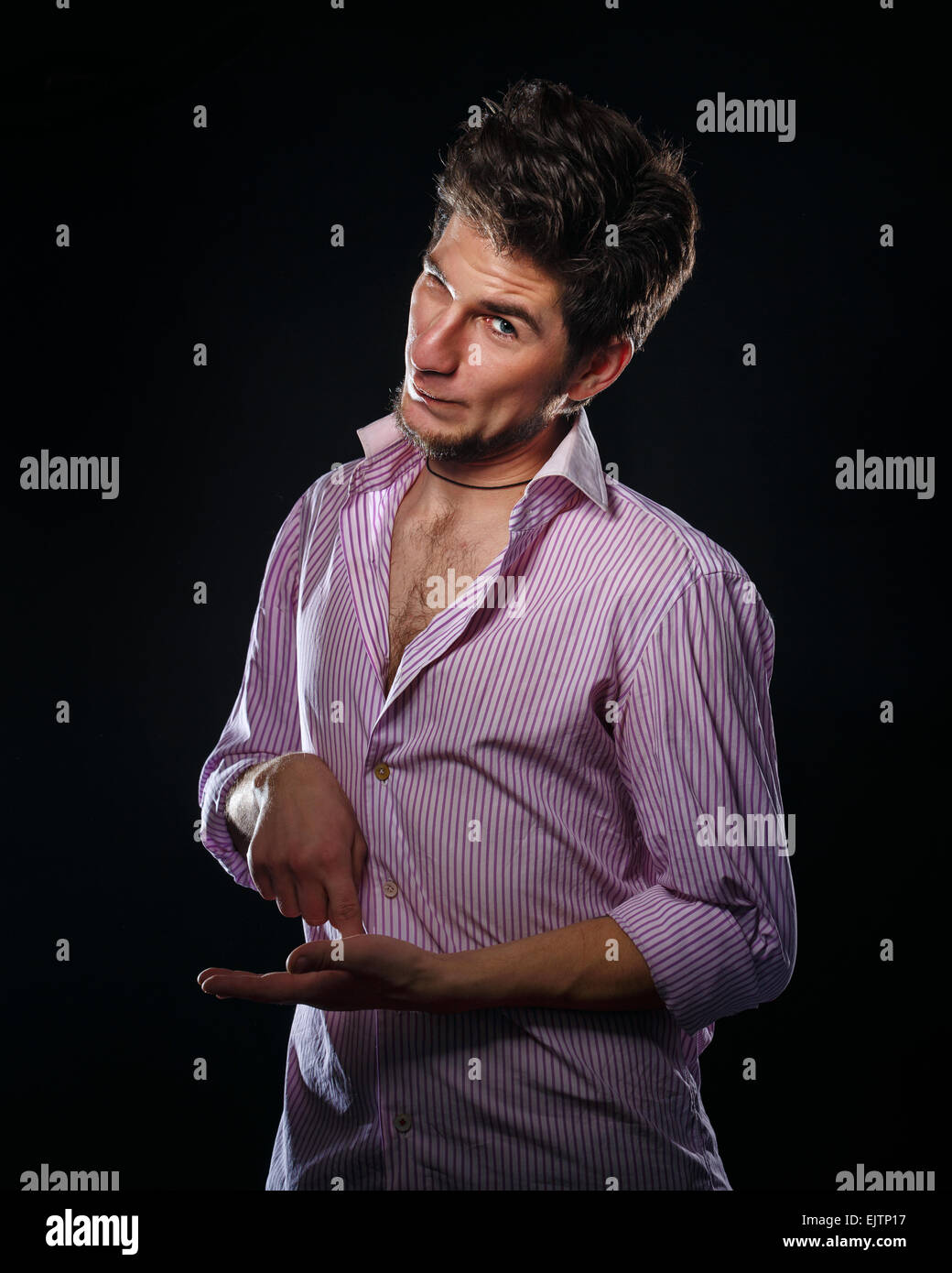 Portrait of a young shy man on a black background in the studio. A man wearing a shirt. Stock Photo