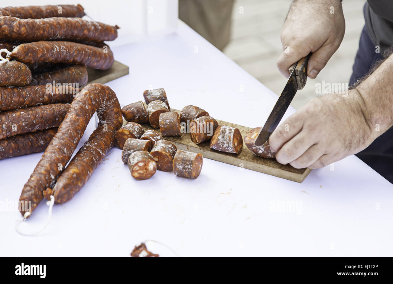 Cutting sausage with a knife, detail of a chef cutting food Stock Photo