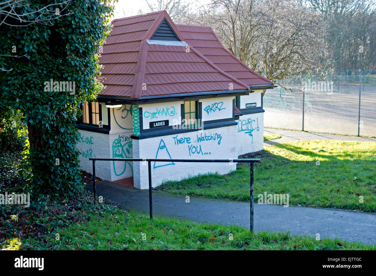 Toilet block in a park covered in poorly spelled graffiti. Stock Photo