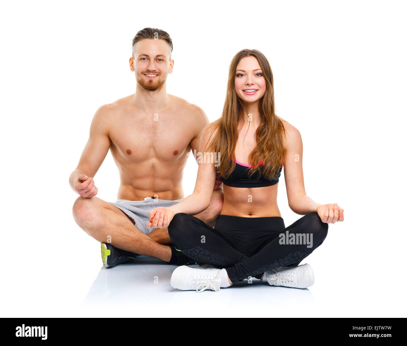 Happy athletic couple - man and woman practicing yoga, doing exercise for relaxation Stock Photo