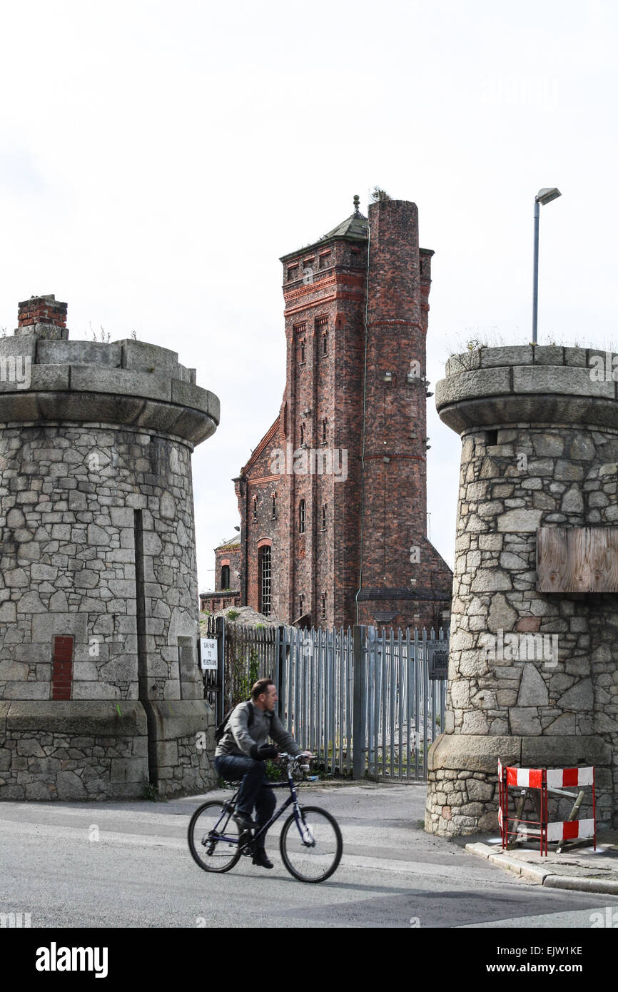Man cycling past old dock entrance towers on Regent Road, Dock road in Liverpool, UK Stock Photo