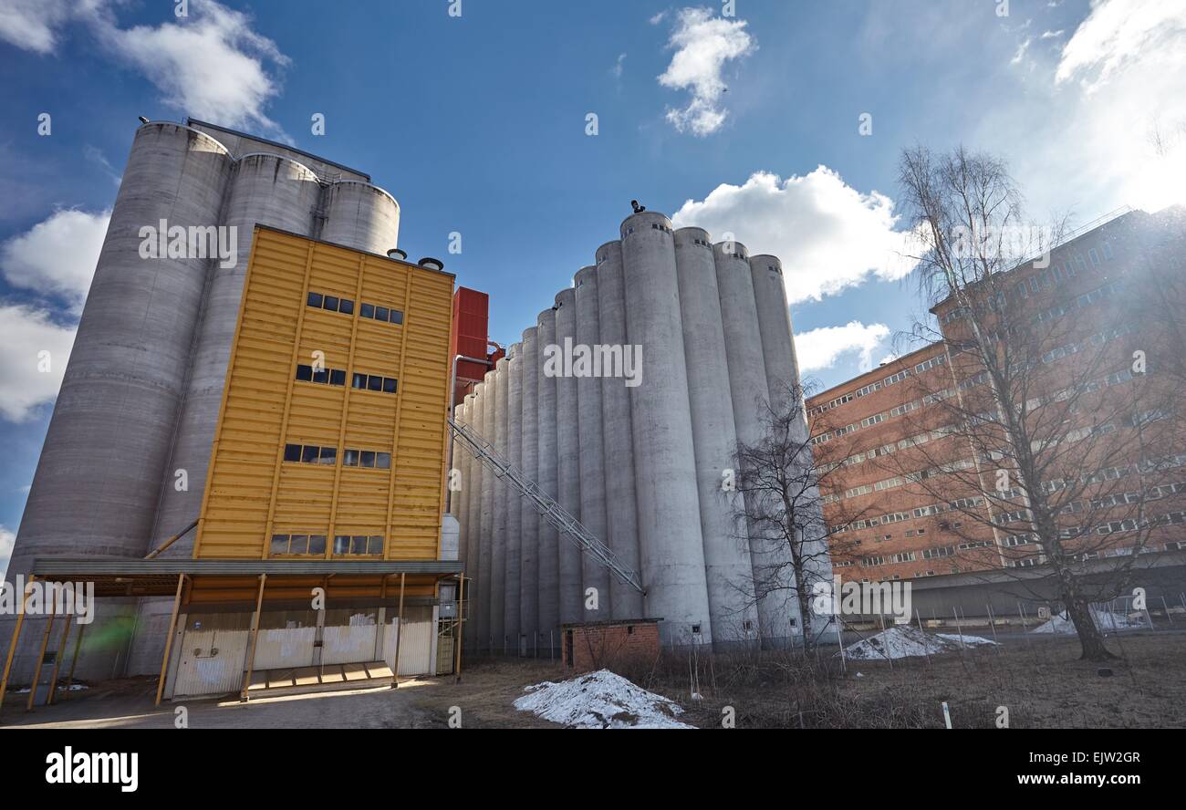Factory exterior with big concrete grain silos and manufacturing building in Finland on a sunny spring day. This majestic old in Stock Photo