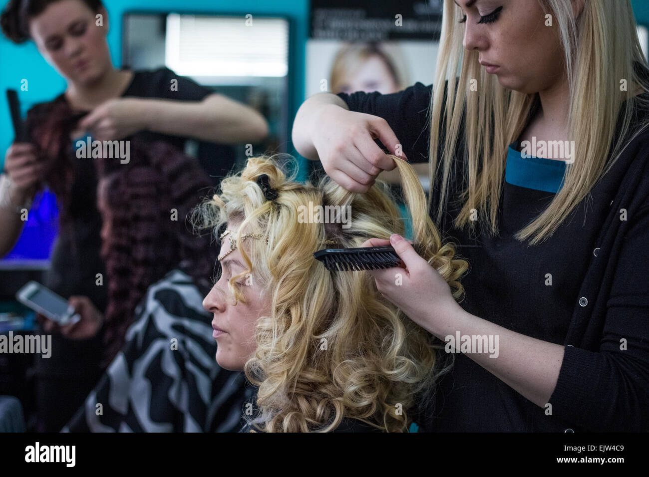 Hairdressers Working In A Salon In Uniform On Female Models With