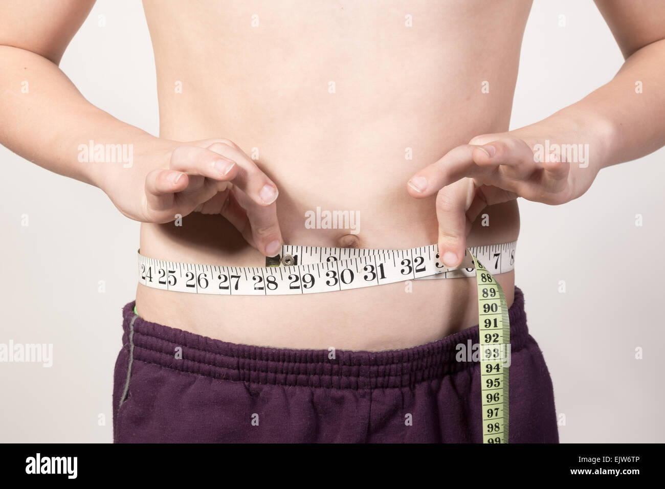 White Teenage boy measuring his stomach. Studio shot Stock Photo