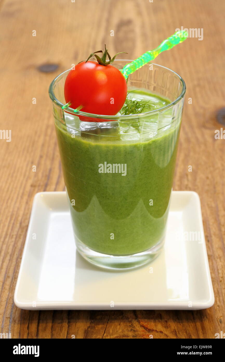 Green spinach smoothie and small red tomato, vertical Stock Photo