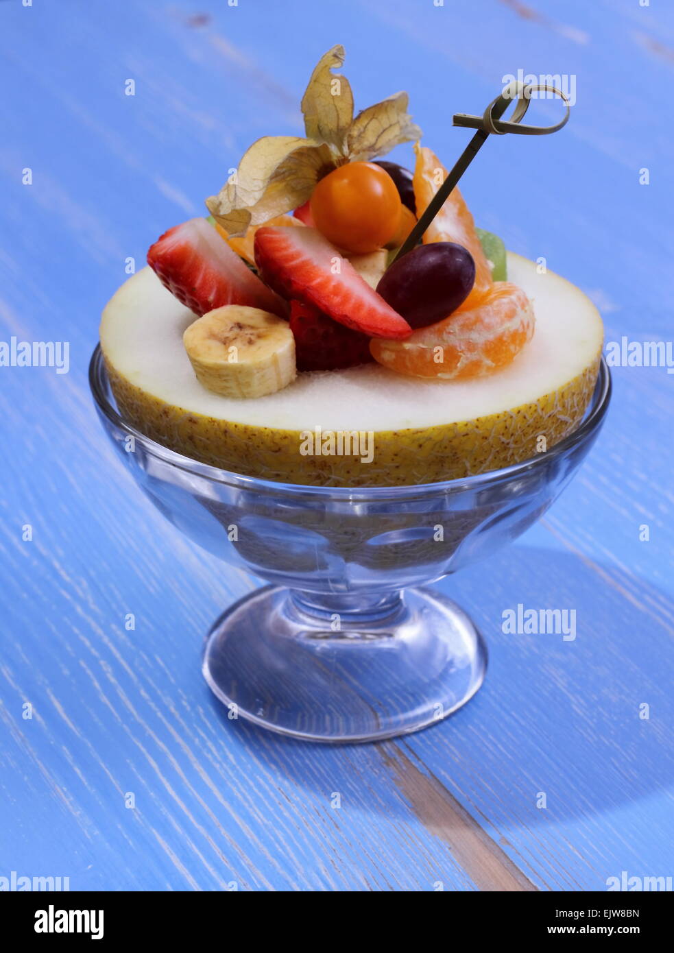 Galia melon filled with summer fruits, healthy eating, blue background