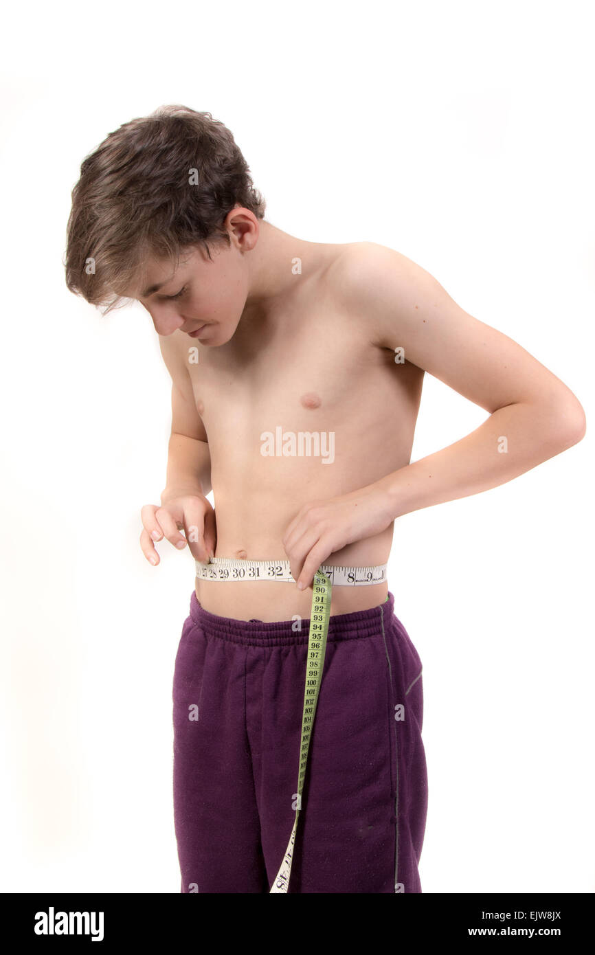 Teenage boy measuring his stomach. Studio shot Stock Photo