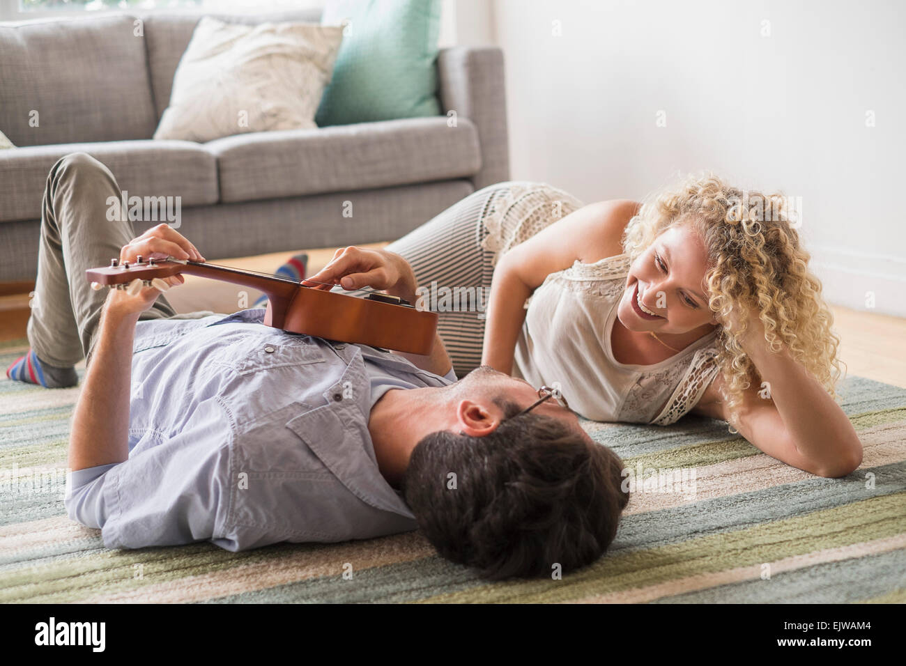 Couple lying on floor playing ukulele Stock Photo