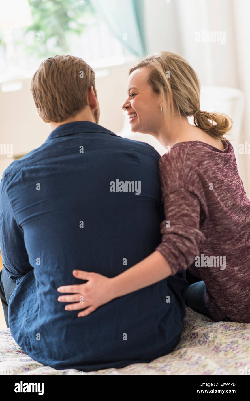 Rear view of young couple sitting on bed Stock Photo