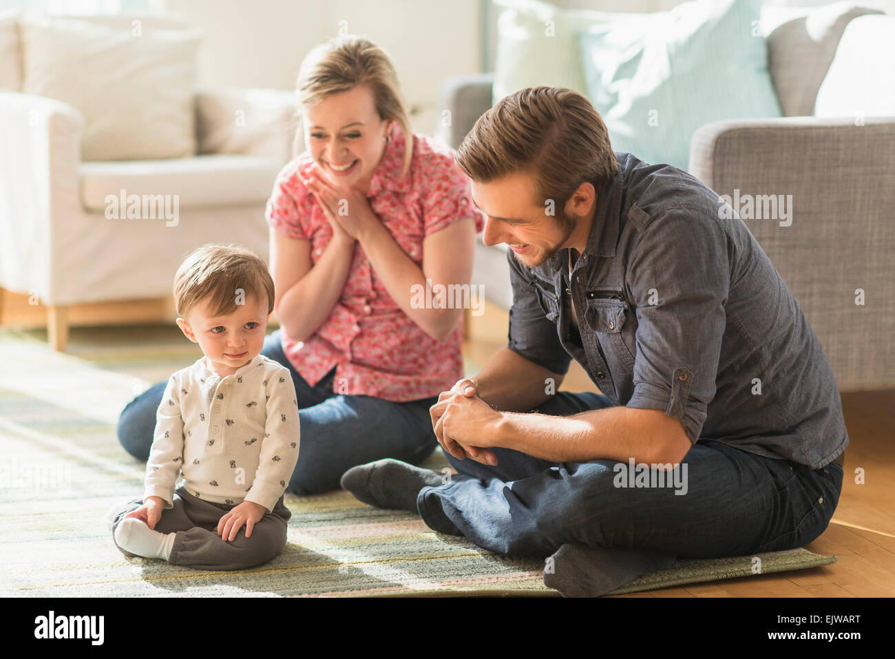 Happy parents sitting with little son (2-3 years) on floor Stock Photo