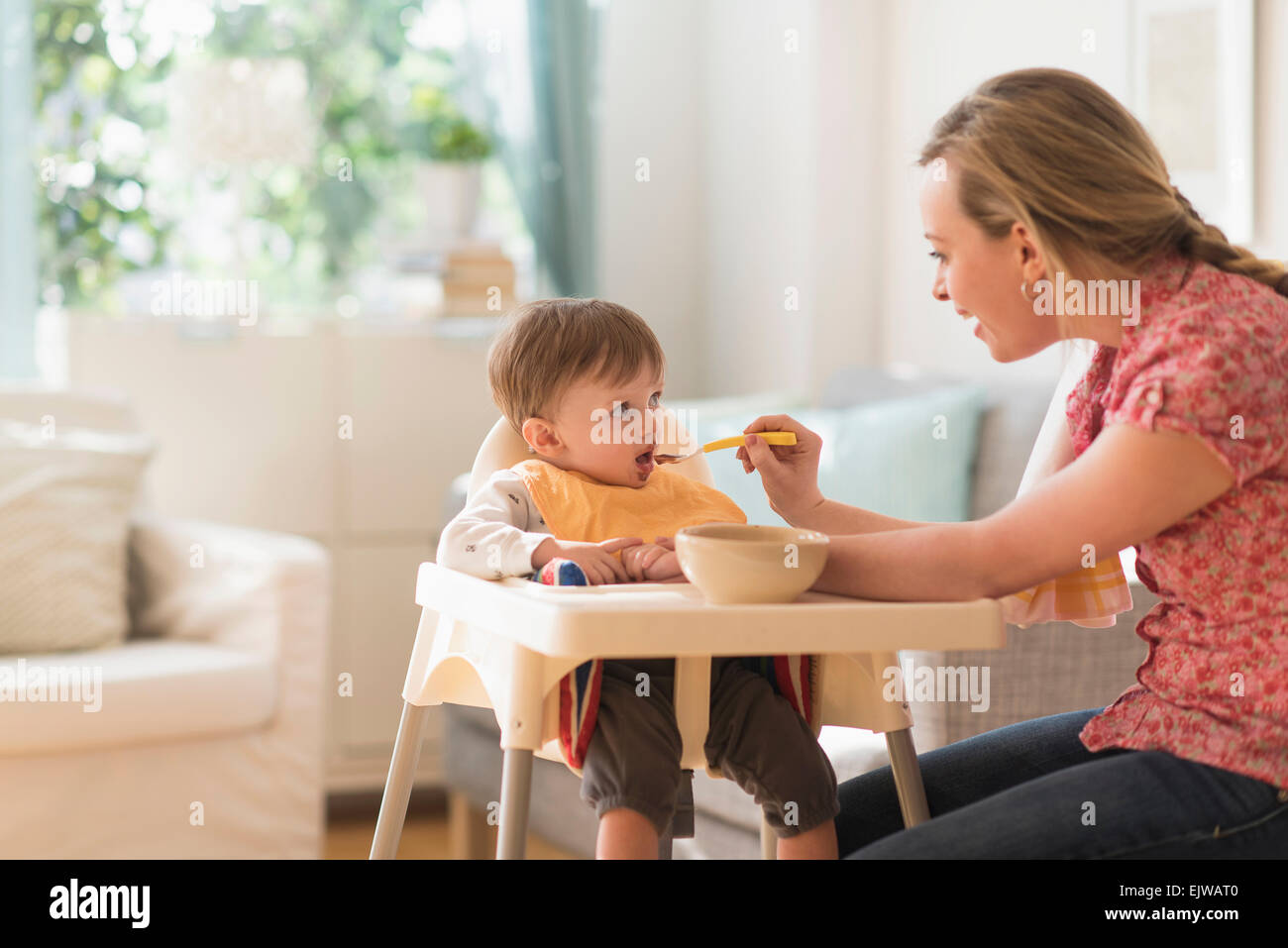 Mother feeding little boy (2-3 years) in high chair Stock Photo