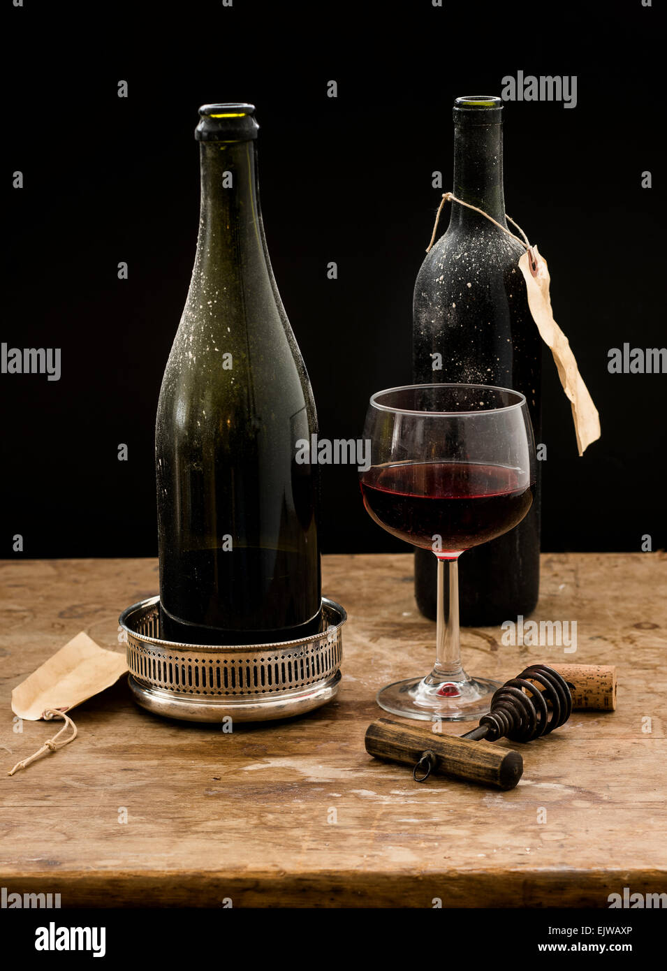 Still life with red wine glass and bottles on wooden table, studio shot Stock Photo