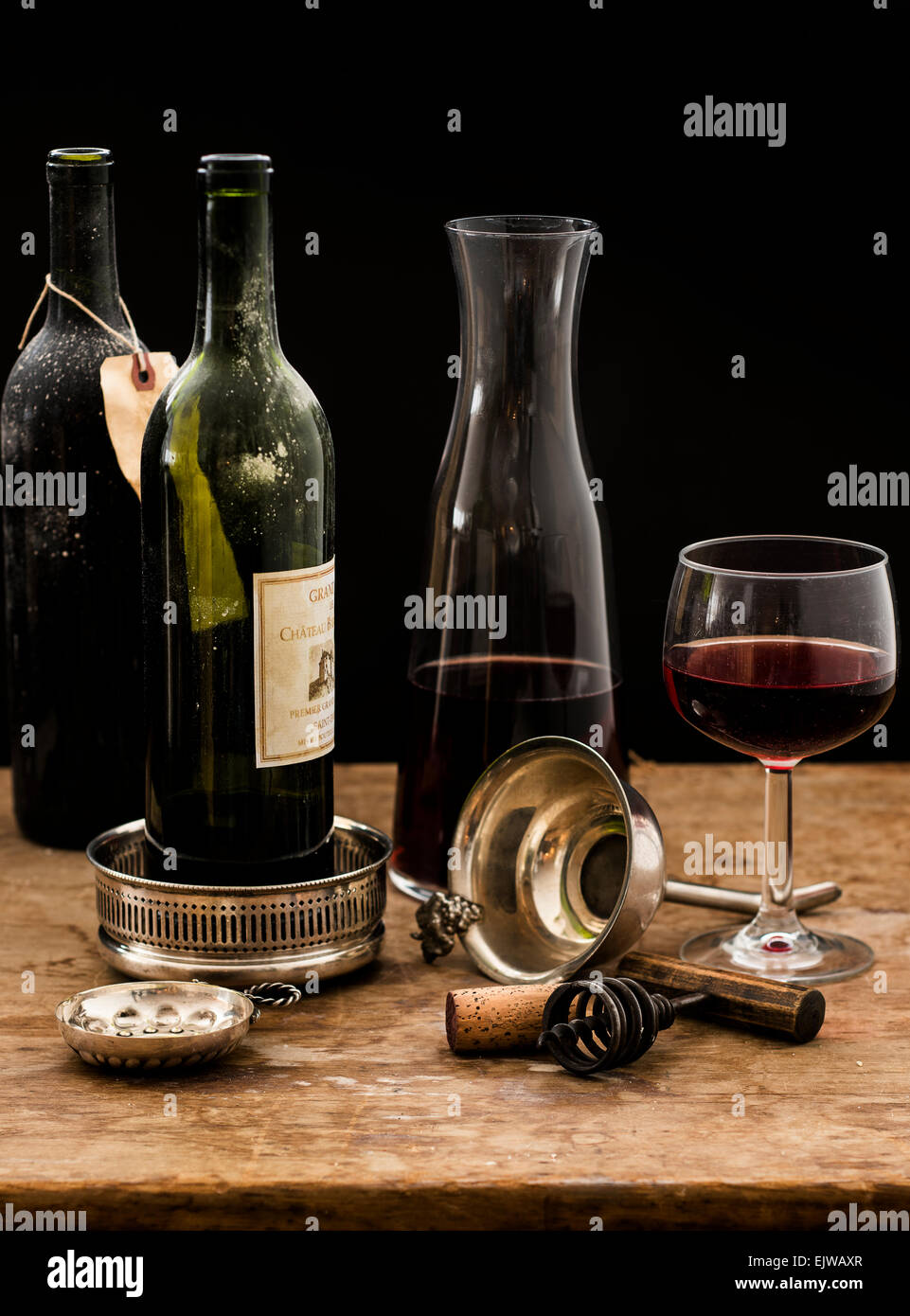 Still life with red wine glass, carafe and bottles on wooden table, studio shot Stock Photo