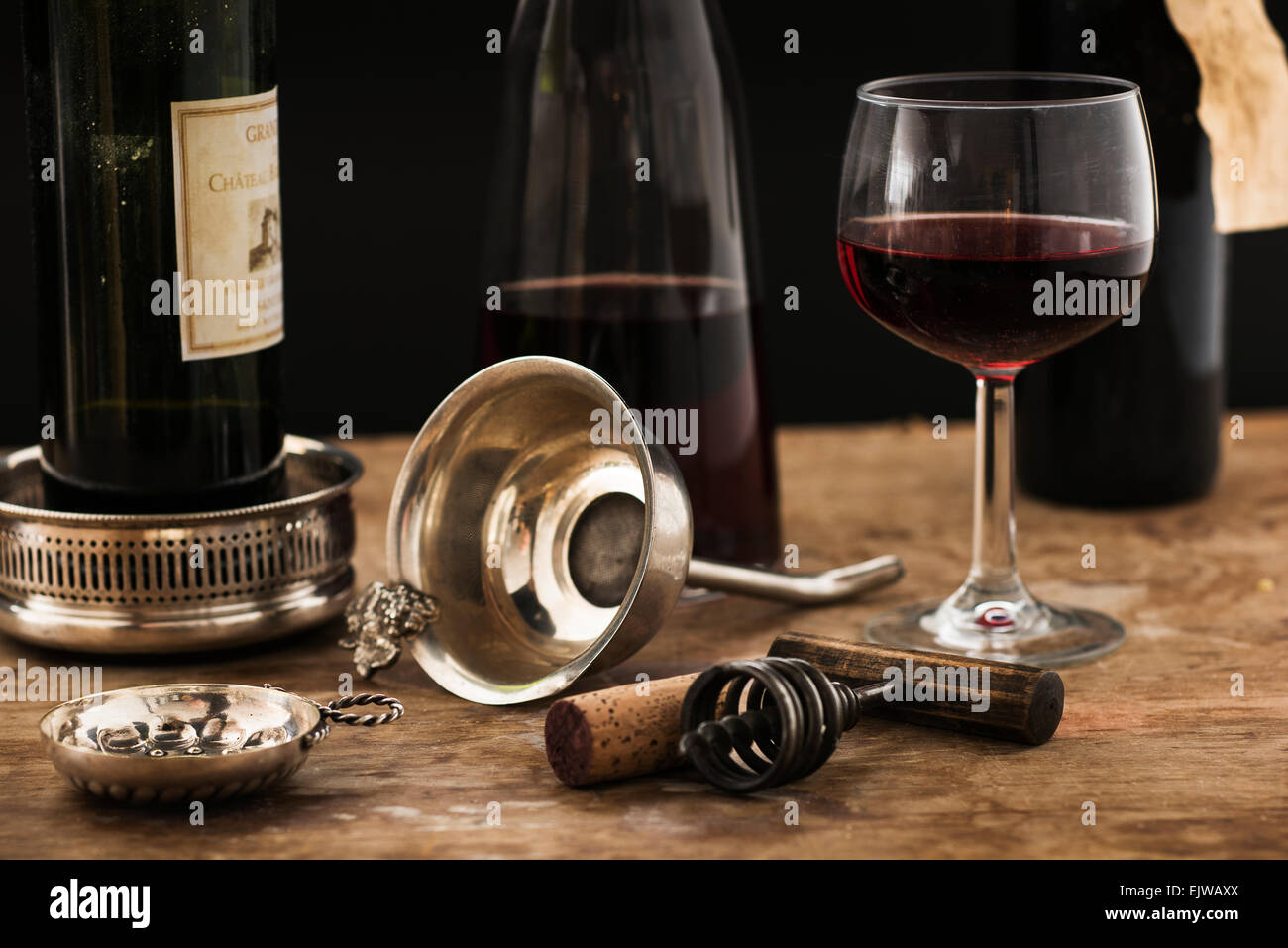 Still life with red wine glass, carafe and bottle on wooden table