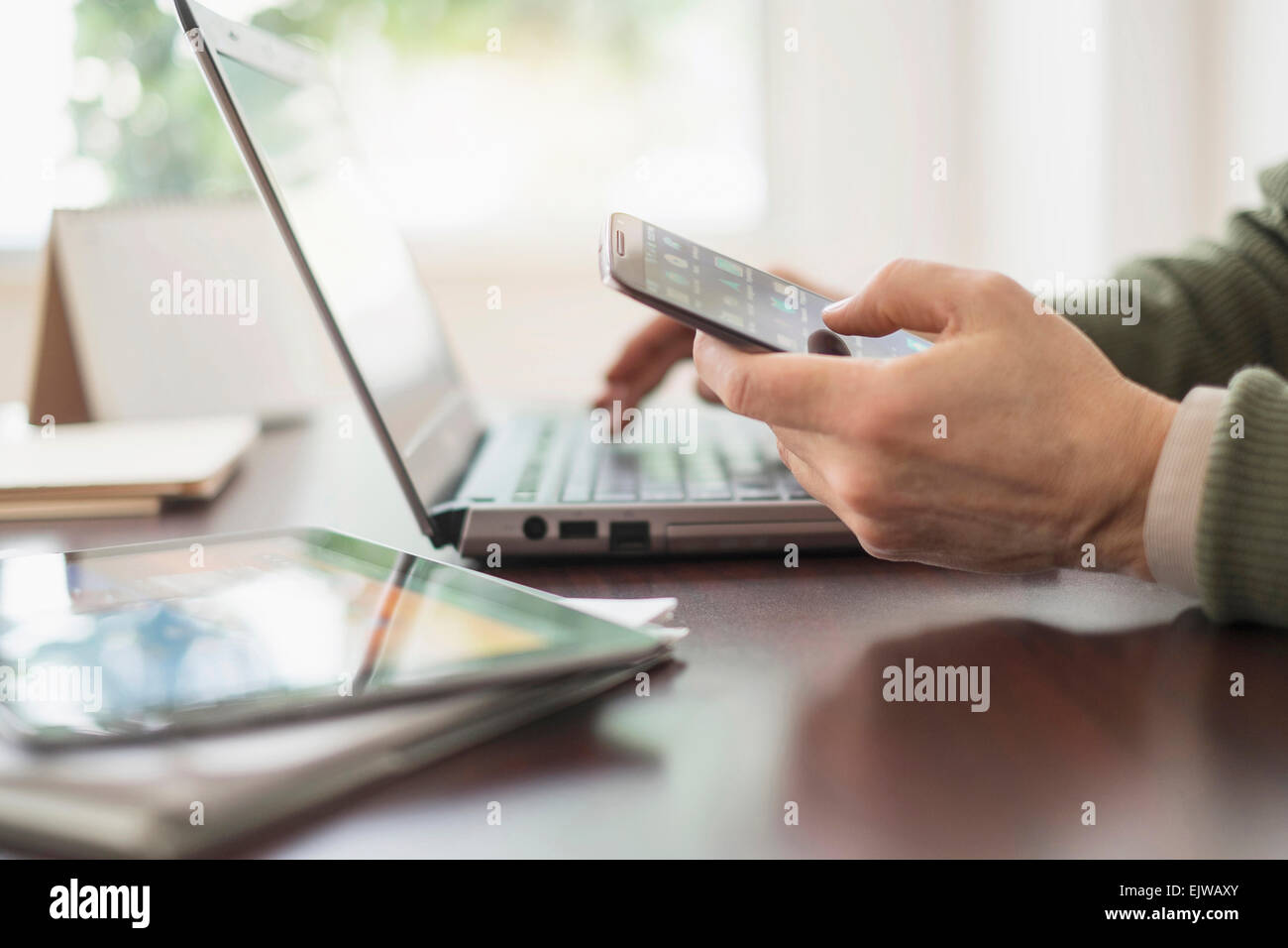 Close up of man's hands working at desk with electronic devices Stock Photo