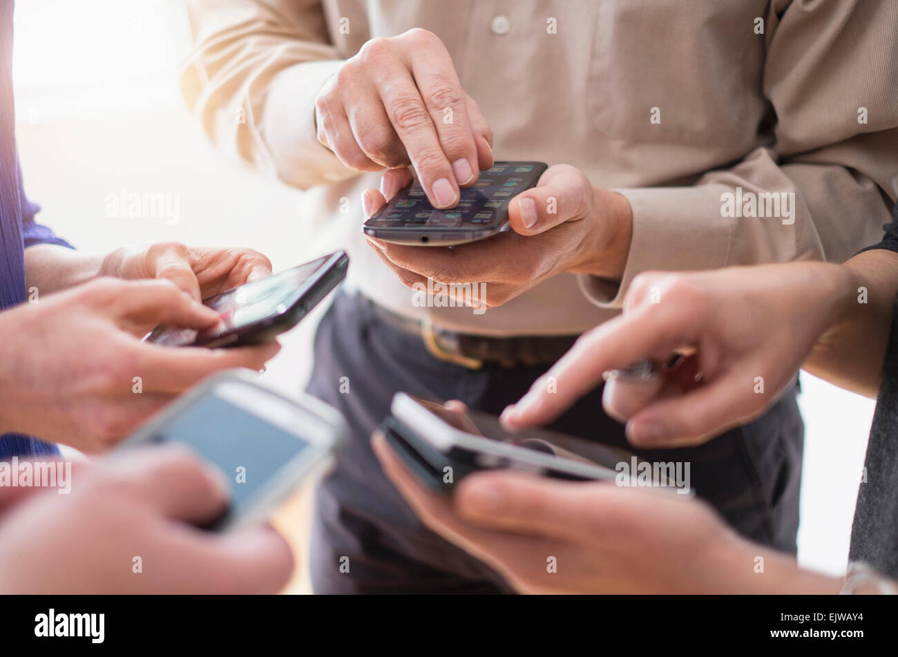 Close up of hands of men and women using smartphones together Stock Photo