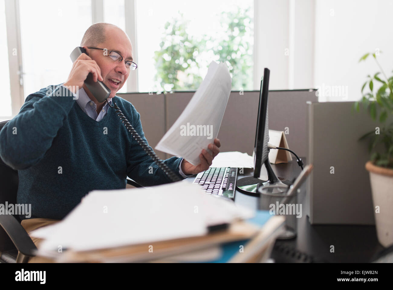 Mature businessman using landline phone in office Stock Photo Alamy