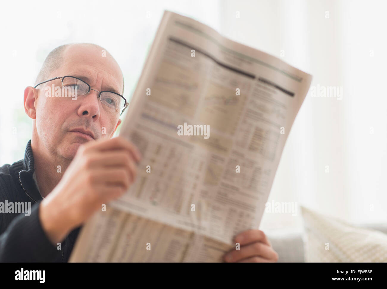 Mature man reading newspaper on sofa Stock Photo