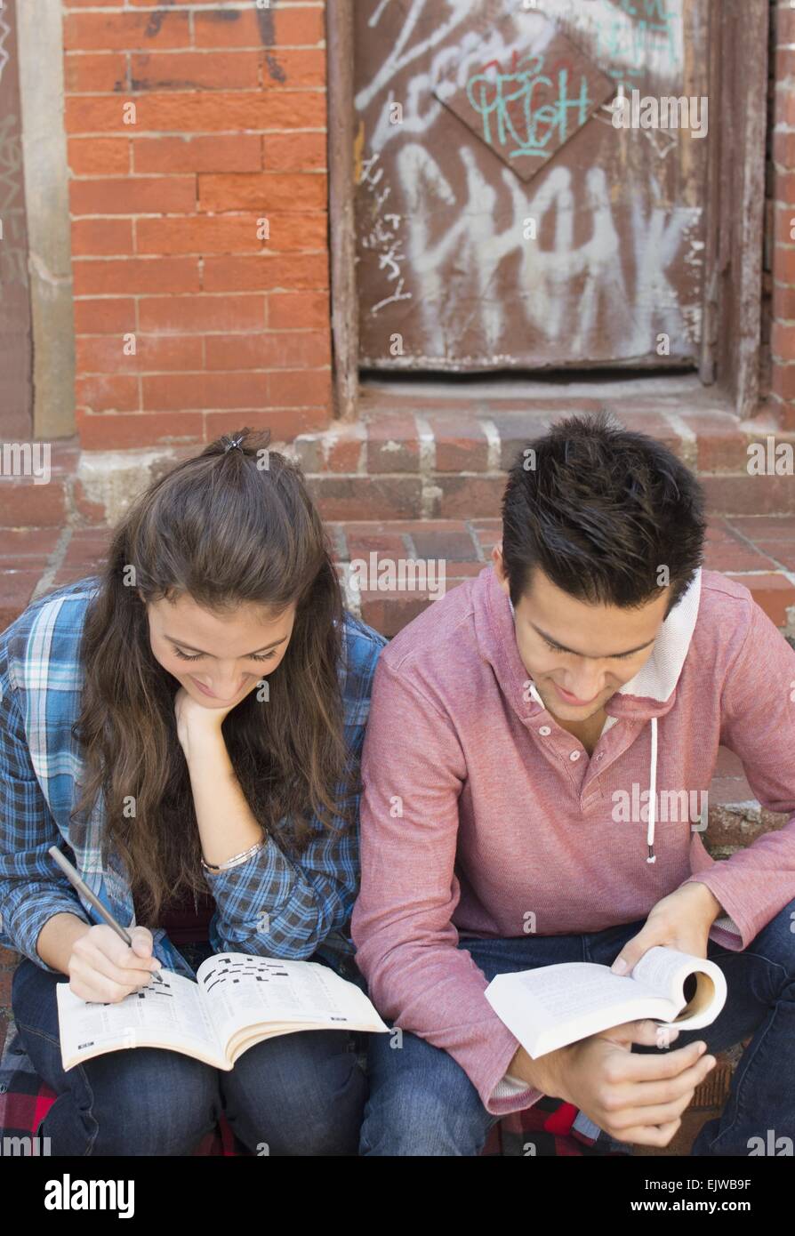 USA, New York State, New York City, Brooklyn, Young couple reading book and doing crossword Stock Photo