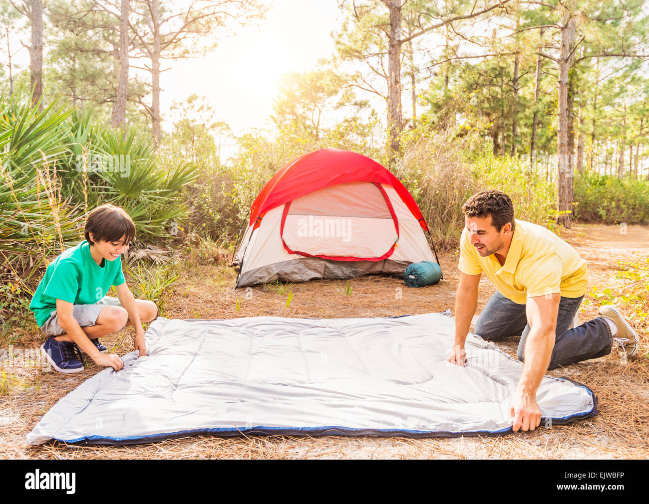 USA, Florida, Jupiter, Father and son (12-13) preparing sleeping bag for camping Stock Photo
