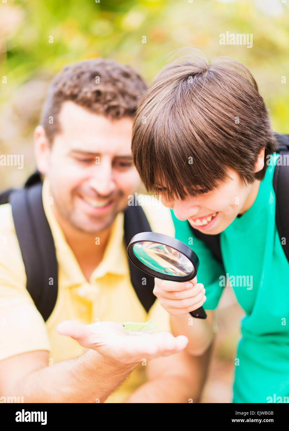 USA, Florida, Jupiter, Father and son (12-13) watching insect with magnifying glass Stock Photo