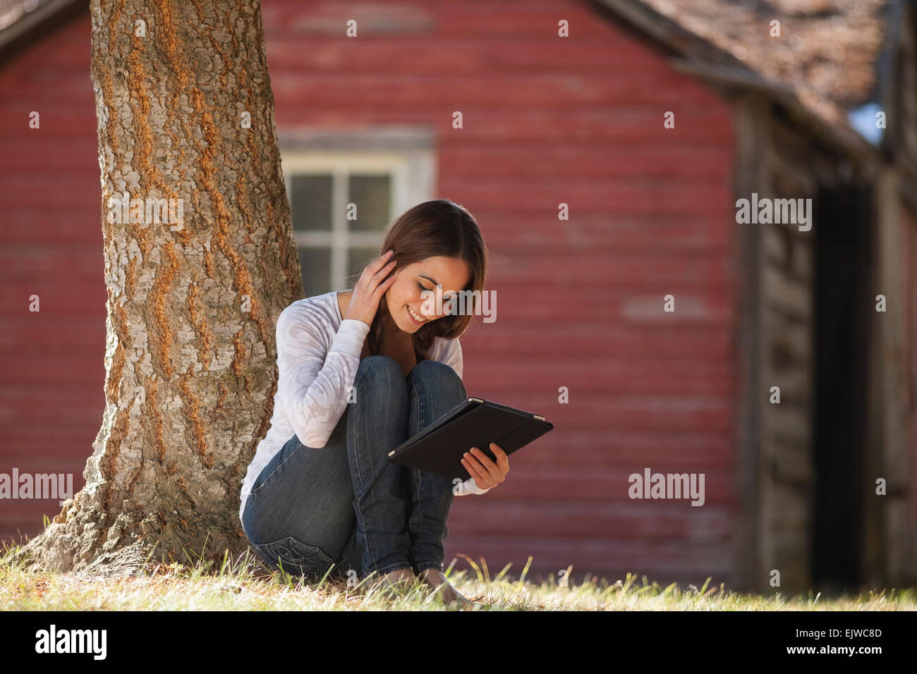 USA, Montana, Whitefish, Woman with tablet sitting under tree Stock Photo