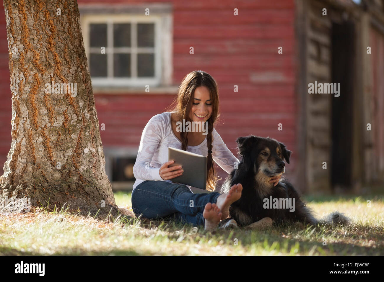 USA, Montana, Whitefish, Woman sitting with dog under tree Stock Photo