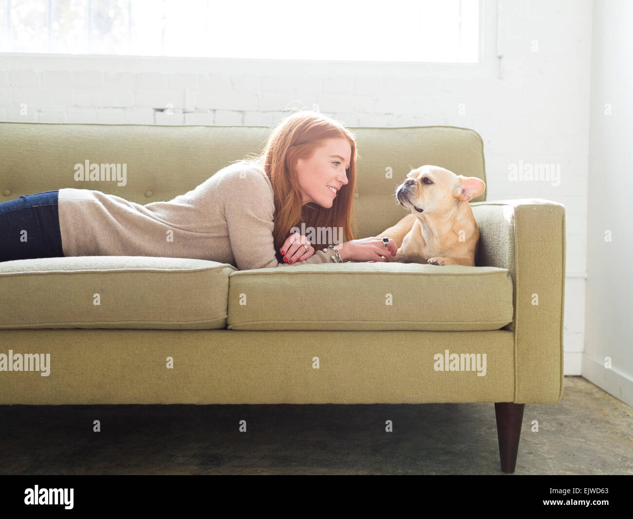 Woman and pug lying on sofa Stock Photo