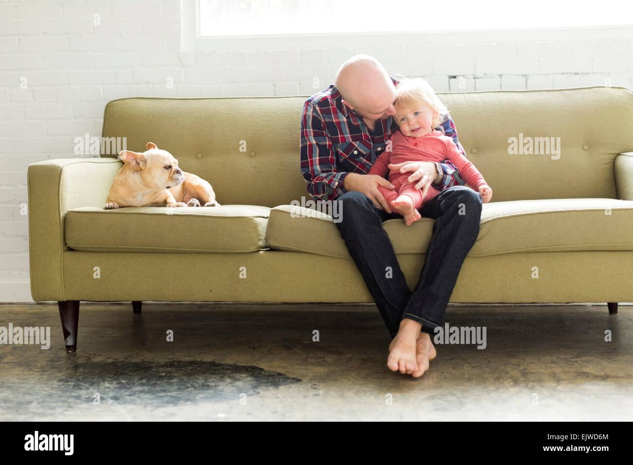Father sitting on sofa embracing baby son (2-3) Stock Photo
