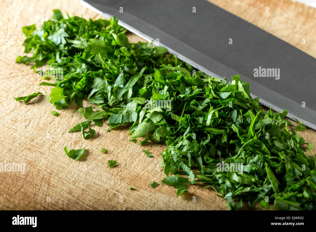 Chopped parsley leaf with a knife on a wooden table Stock Photo