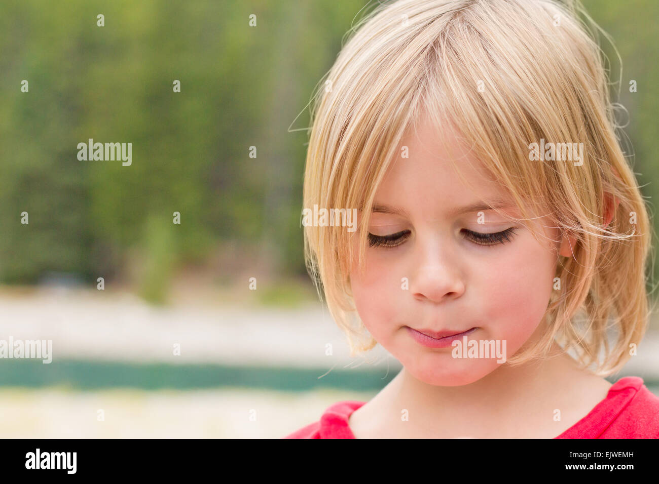 Timid Little Girl Looking Down with a Shy Look Stock Photo