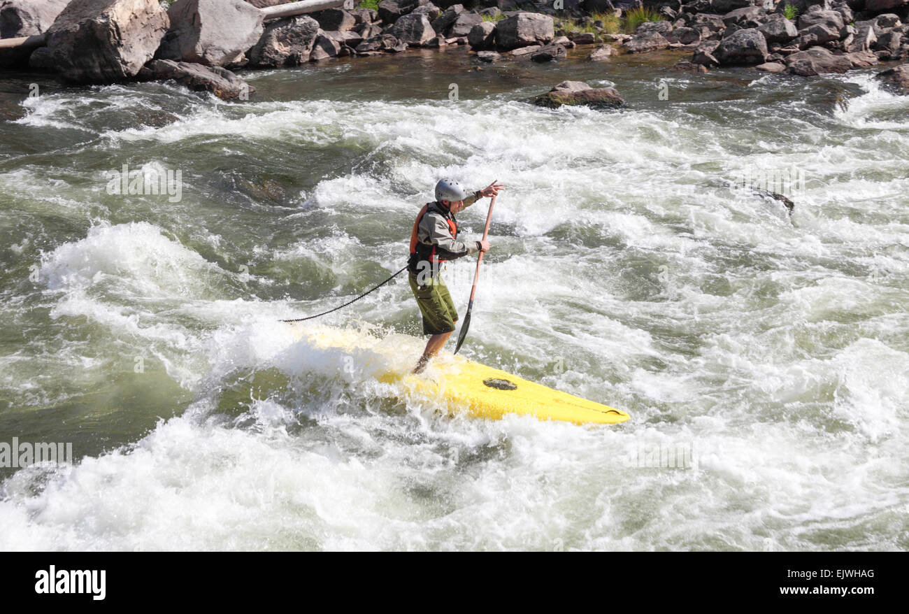 Man standing on board paddles through rapids in Glenwood Canyon Stock Photo