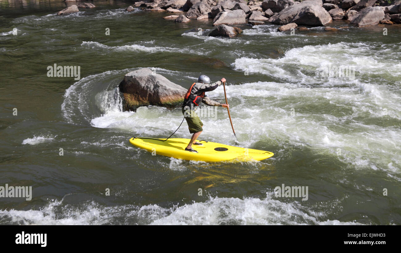 Man standing on board goes down rapids in Glenwood Canyon Stock Photo