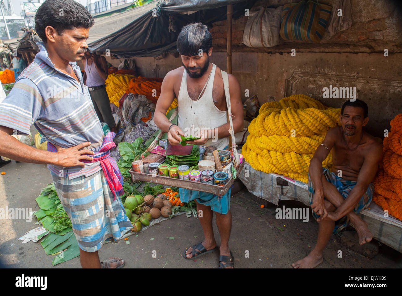 A paan vendor prepares a mixture of tobacco and areca nut on a betel