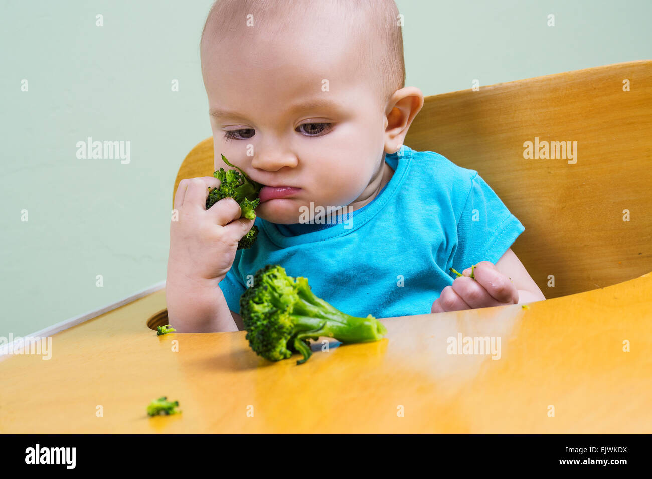 Funny baby tasting broccoli Stock Photo