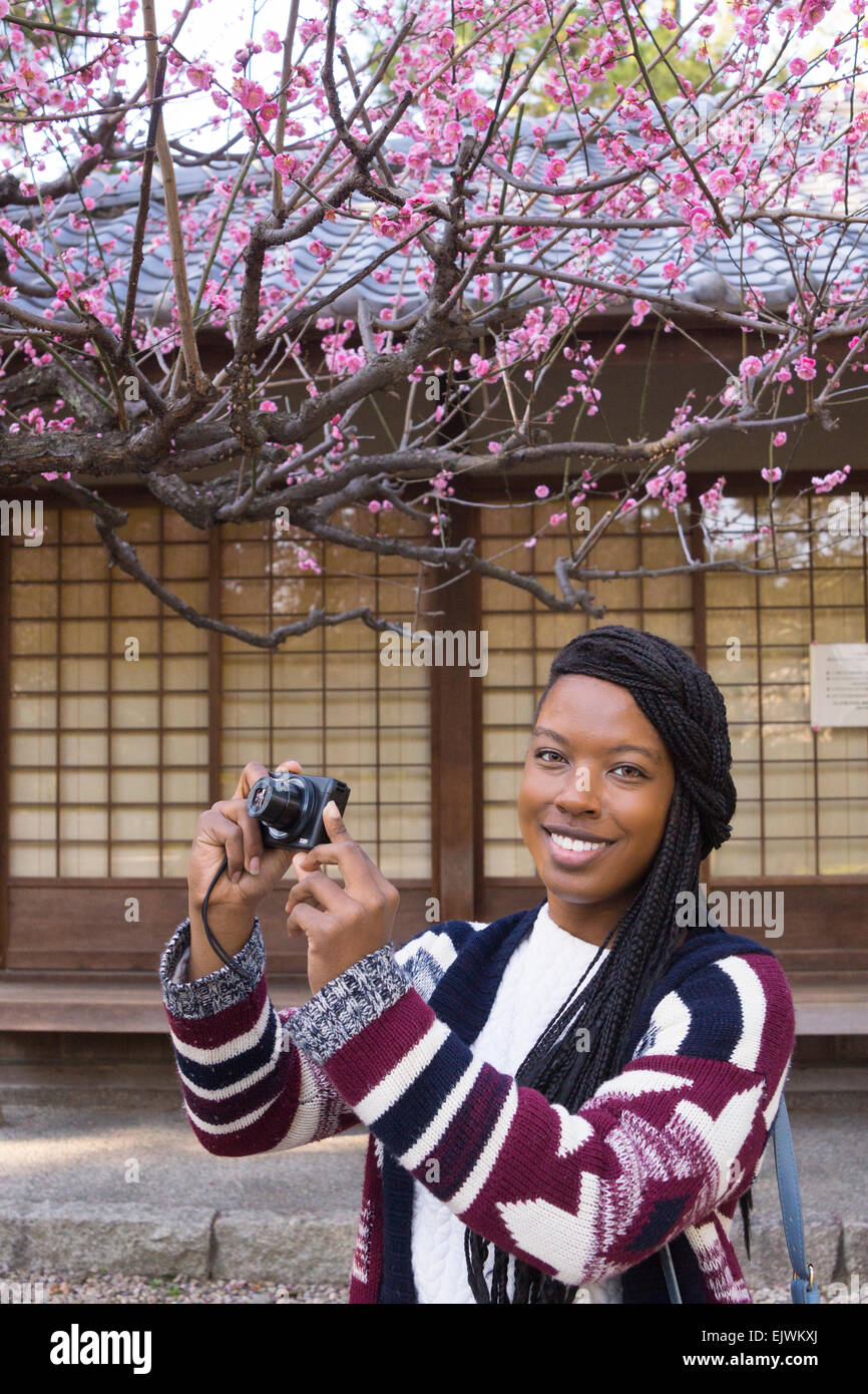 A young lady traveling in Japan enjoying plum flowers at early bloom at Nagoya Castle. Stock Photo