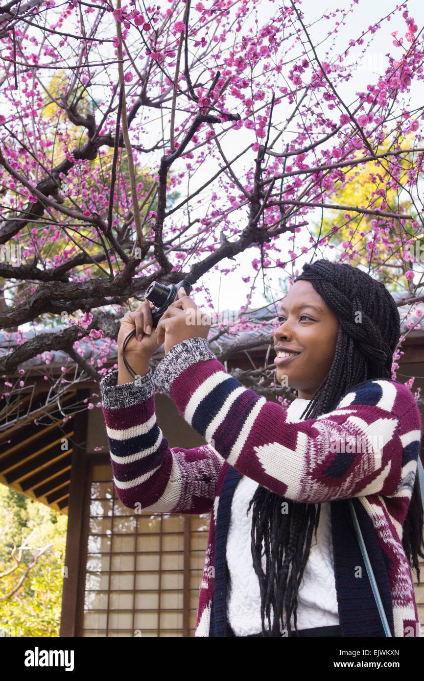 A young lady traveling in Japan enjoying plum flowers at early bloom at Nagoya Castle. Stock Photo