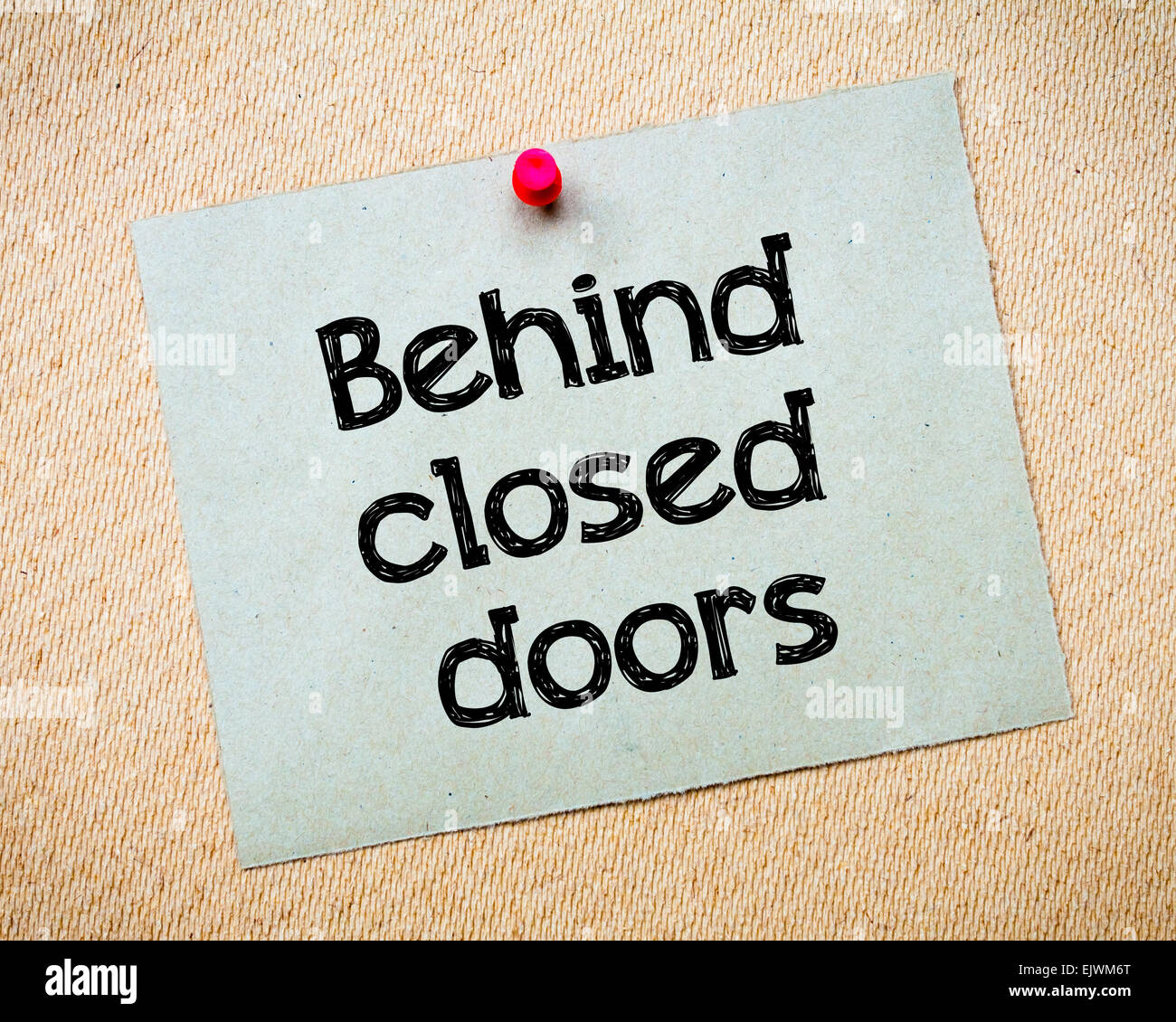 Behind closed doors Message. Recycled paper note pinned on cork board. Concept Image Stock Photo