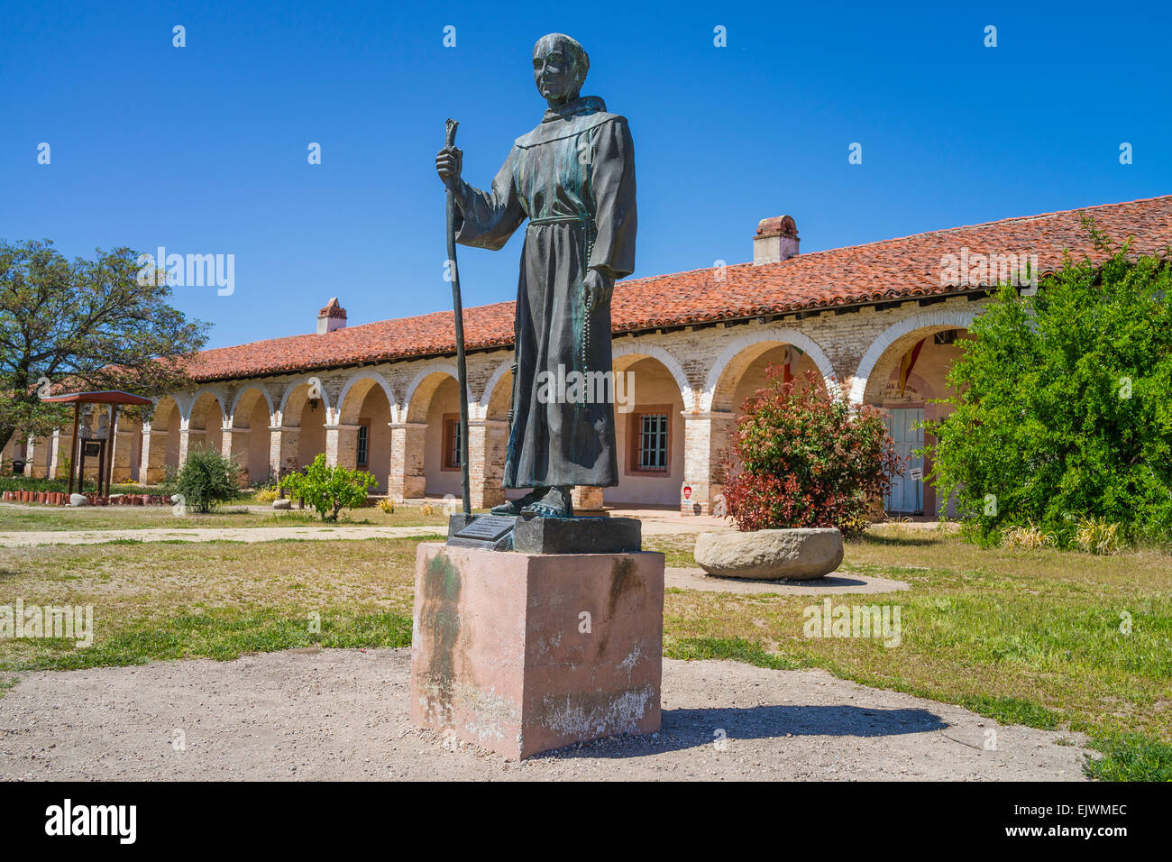 Bronze statue of Fr. Junipero Serra in front of the red tile roof and