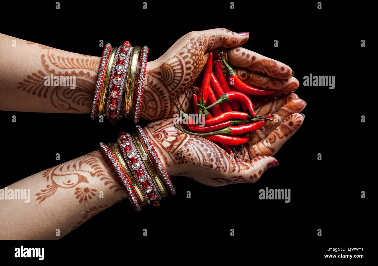 Woman hands with henna holding red chili isolated on black background with clipping path Stock Photo