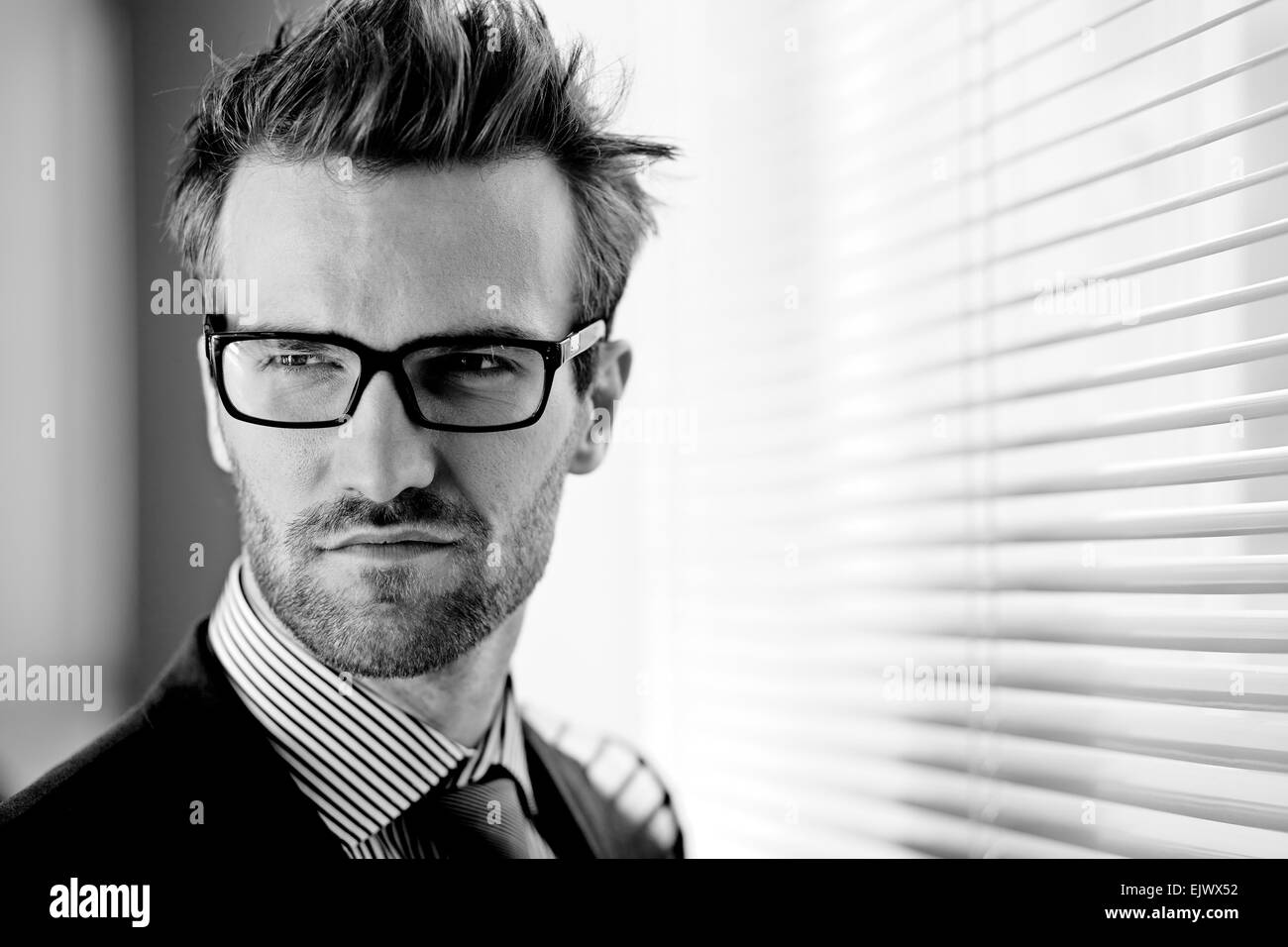 Posh businessman in eyeglasses on background of jalousie Stock Photo