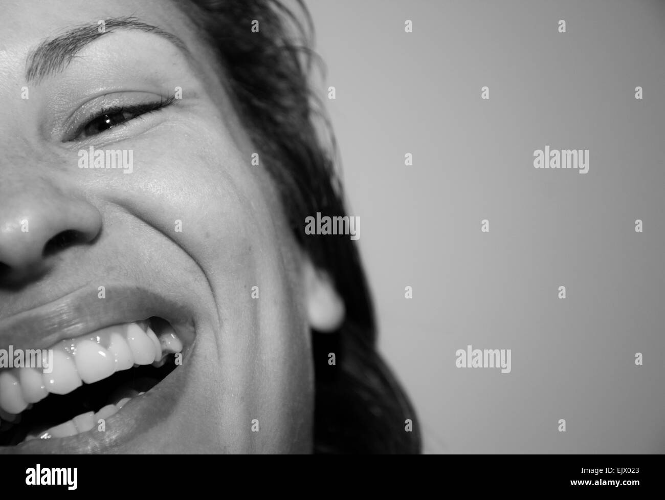 Closeup portrait of a pretty young woman laughing out loud monochrome indoors Stock Photo
