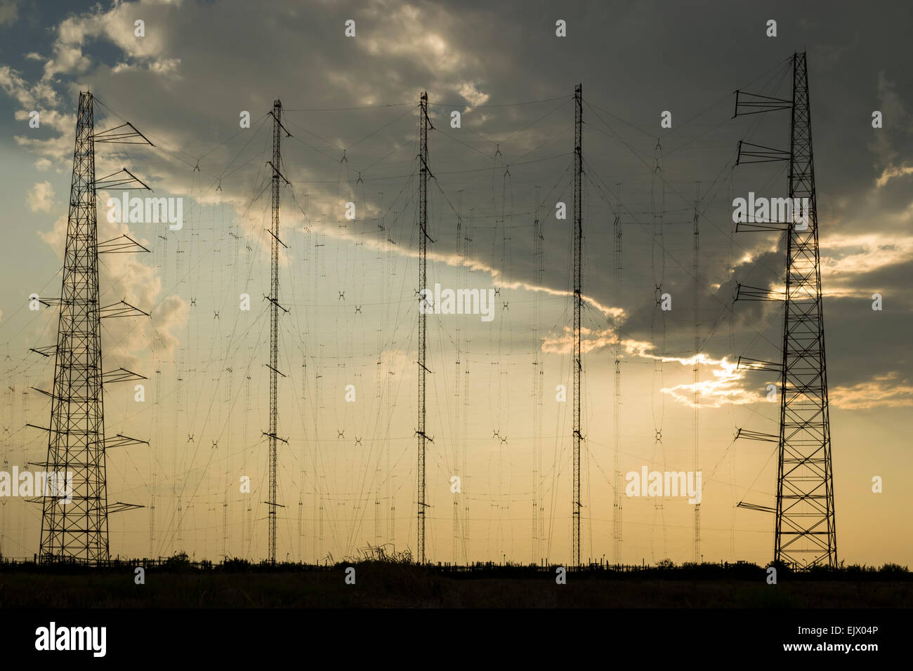 Array of radio communication antennas on cloudy sky background, at sunset Stock Photo